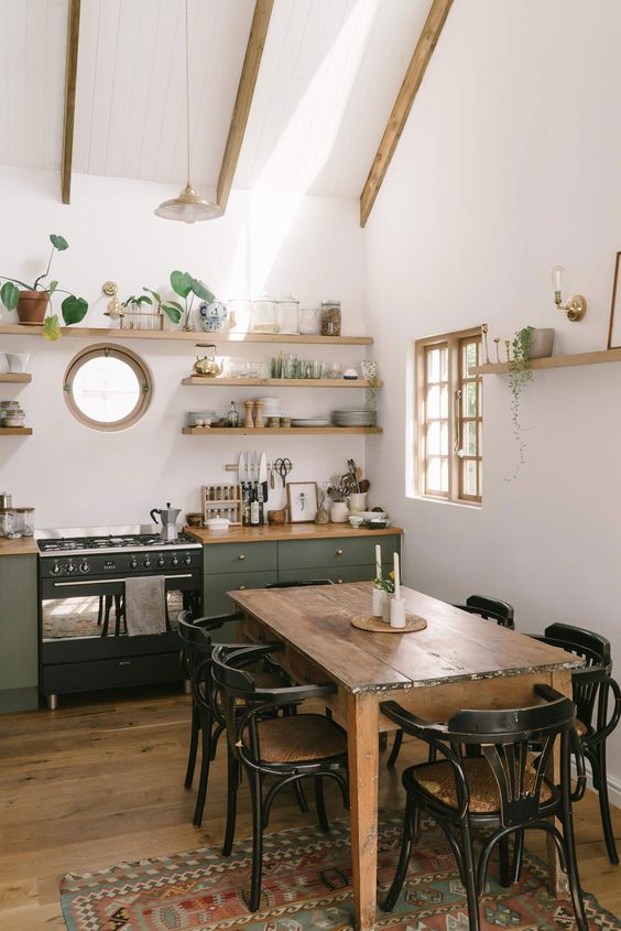 a cool cottage kitchen with grey cabinets and butcherblock countertops, a small earing zone and decorative woodne beams