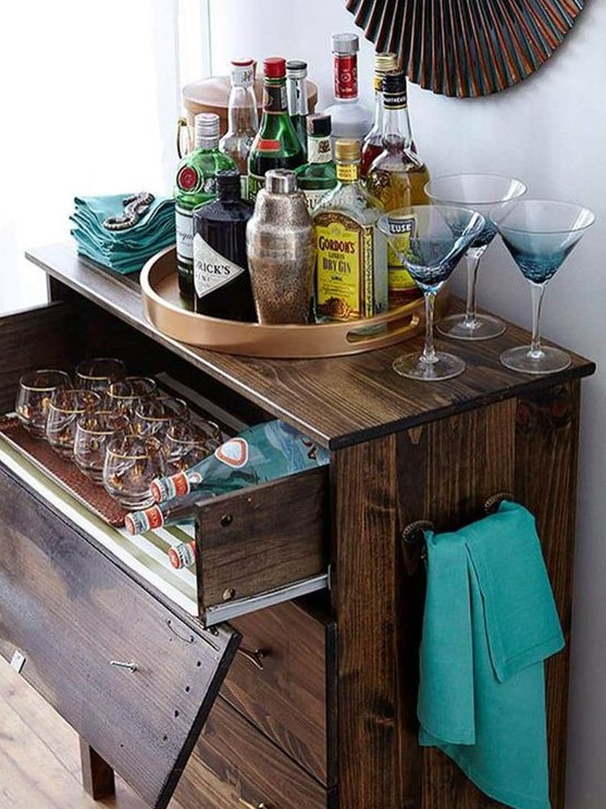 a dark stained IKEA Tarva dresser with a pullout drawer for stashing glasses and bottles is a chic rustic bar idea