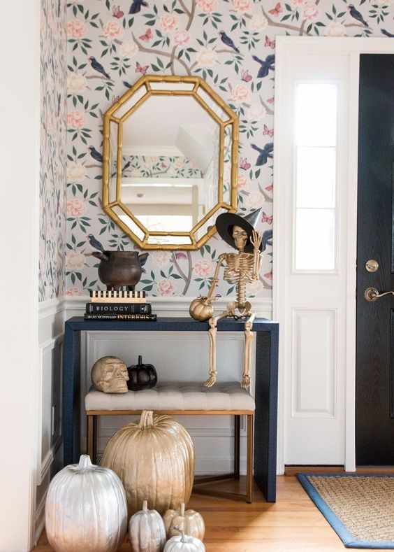 a glam Halloween console table with silver, gold and black pumpkins, a gold skeleton in a witch hat and a skull