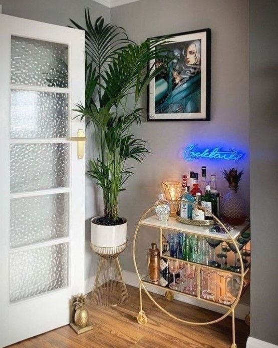 a glam home bar nook with a gold round bar with open storage spaces and a blue neon light over it