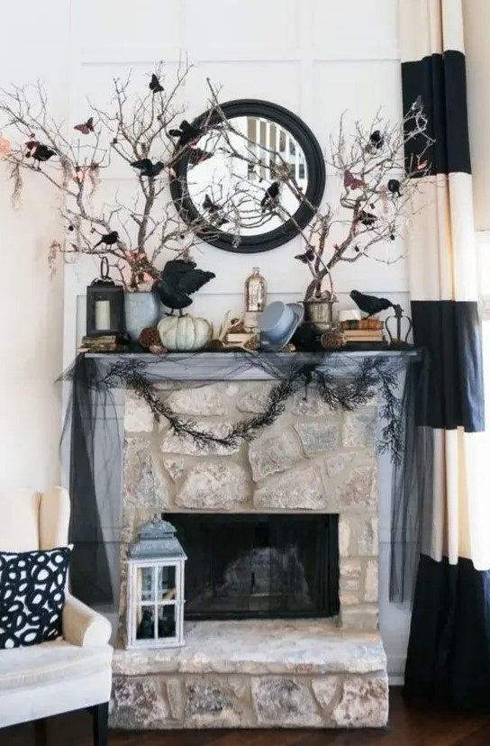 a haunted Halloween mantel with blackbirds, branches, garlands, a mirror and some pumpkins