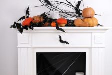 a modern Halloween fireplace with black bats, pumpkins, pillar candles and a bucket with a pumpkin