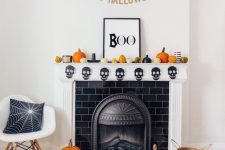 a modern Halloween mantel with a skull banner, pumpkins, a sign and a banner is a lovely idea for the holiday