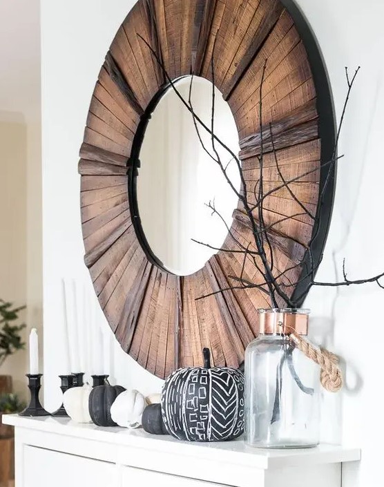 a modern Halloween mantel with black and white pumpkins and branches in a jar plus candles