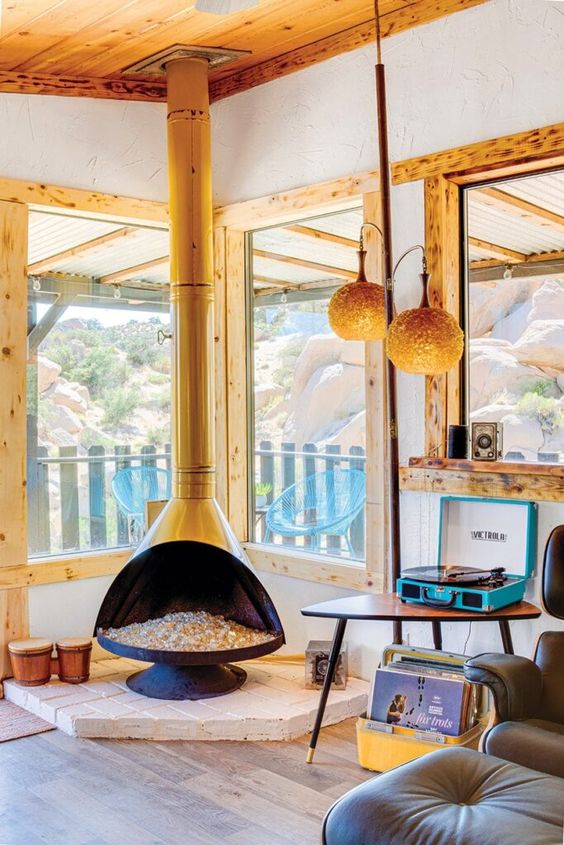 a modern bright nook with large windows, a yellow Malm fireplace, a coffee table, a brown chair and a footrest, pendant lamps