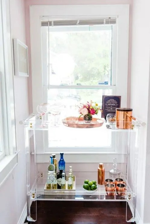 a modern home bar of clear acryl, with bright blooms and copper barware plus pink glasses for a chic and fresh look