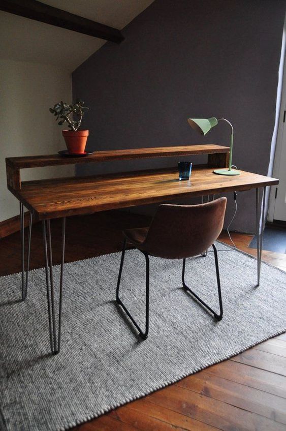 a modern industrial working space with a wooden desk on hairpin legs and a leather metal chair plus a table lamp