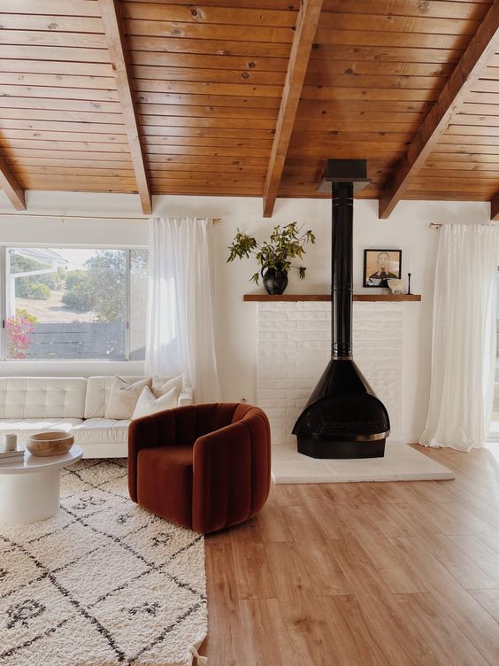 a modern neutral living room dotted with an eye-catchy burgundy chair and a black Malm fireplace that bring color and interest to the room