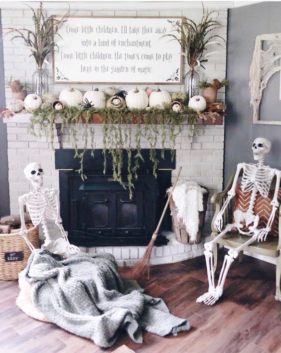 a neutral Halloween fireplace decorated with greenery and white pumpkins, with a skeleton scene in front of it is a cool idea