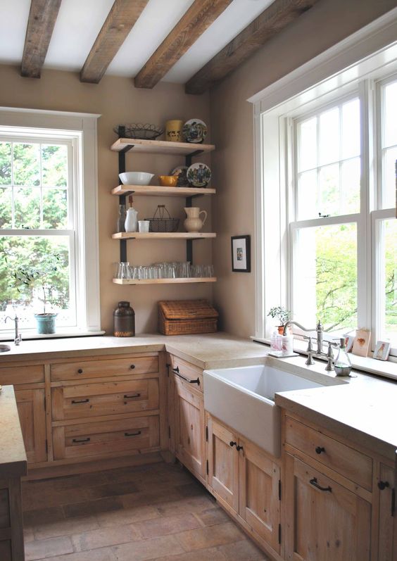 a neutral cottage kitchen with stained cabinets, wooden beams, open shelving and tan stone countertops is a lovely and welcoming space