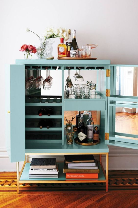 a pretty turquoise cabinet with mirrors inside, with wine bottles and glasses, blooms, a tray with wine and wine glasses