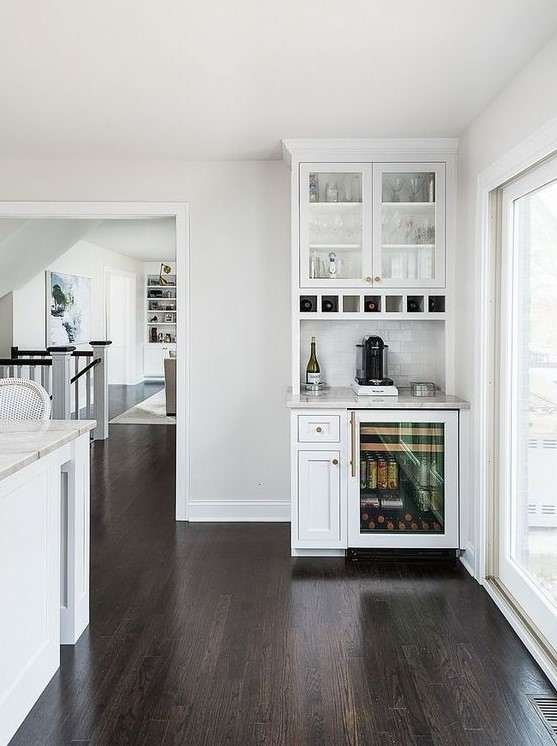 a small white home bar with open and closed storage compartments, a tile backsplash and a fridge for bottles
