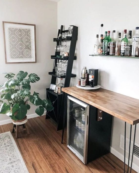 a stylish farmhouse bar with a wall-mounted shelf, a ladder shelf with glasses, a wine cooler and a stained countertop