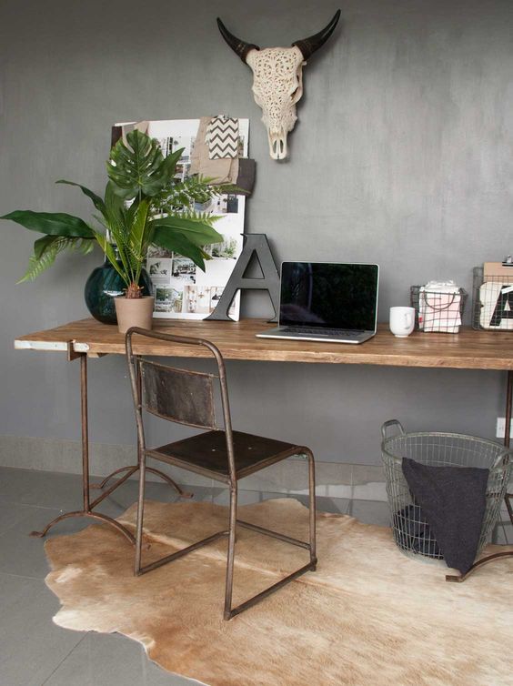 a stylish working nook with a wood and metal vintage desk, a leather and metal chair, some greenery and pretty boho decor