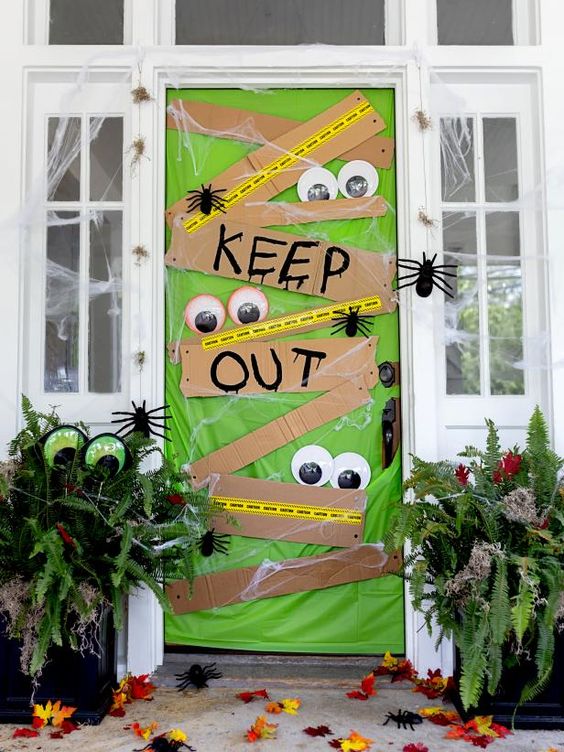 a super bold and catchy front door in green, with signs, googly eyes, spiders is a very fun and colorful idea for Halloween