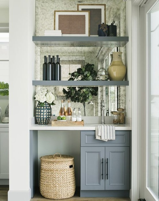 a tiny built-in home bar with a mirror backsplash, open shelves, a cabinet and a sink plus blooms and a basket