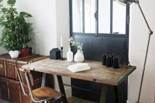 a vintage industrial home office with a desk of aged wood and metal, a matching chair, vintage chests for storage and some greenery