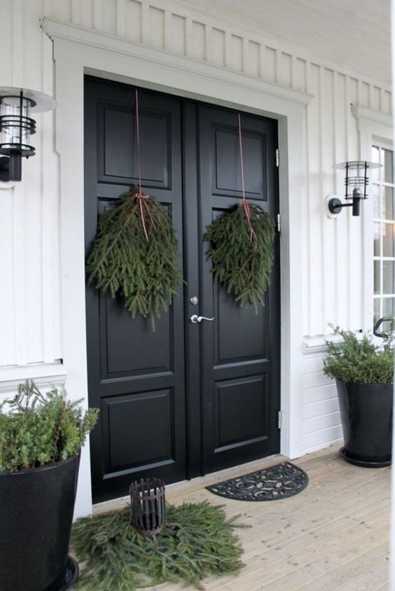 all-natural Christmas front door decor with evergreen posies, some evergreens on the floor and in pots