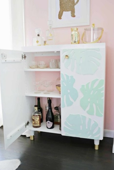 an IKEA Ivar cabinet turned into a stylish kid-proof home bar with dimensional monstera leaves and gilded legs