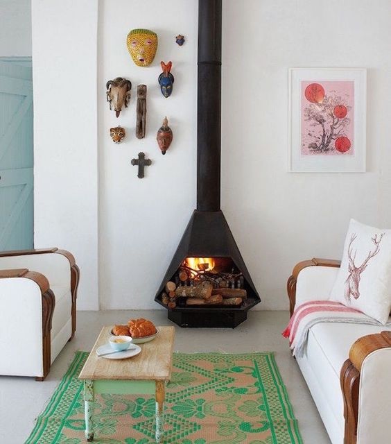 an eclectic living room with white seating furniture, a bright green and pink rug, a shabby chic coffee table and a black Malm fireplace