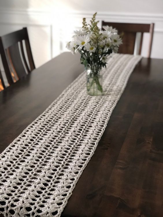 an elegant and airy white crochet table runner is a chic idea for a modern or shabby chic space, it may add charm to a rustic one, too