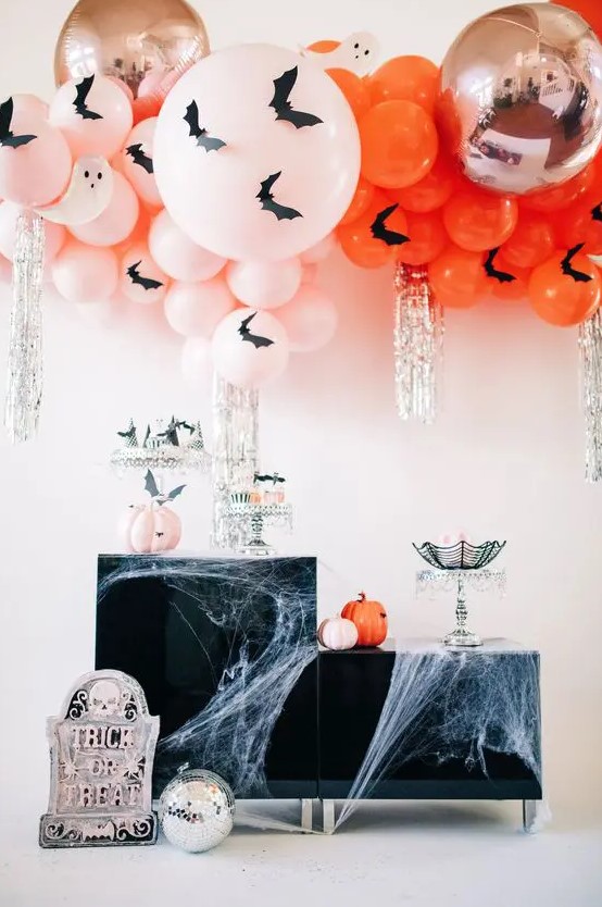 blush and orange balloons with bats, matching pumpkins and silver fringe plus spiderwebs and a gravestone