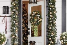 bright and festive Christmas front door decor with evergreen garlands and metallic ornaments, topiaries and candle lanterns