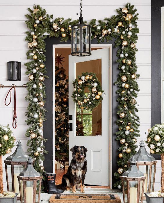 bright and festive Christmas front door decor with evergreen garlands and metallic ornaments, topiaries and candle lanterns