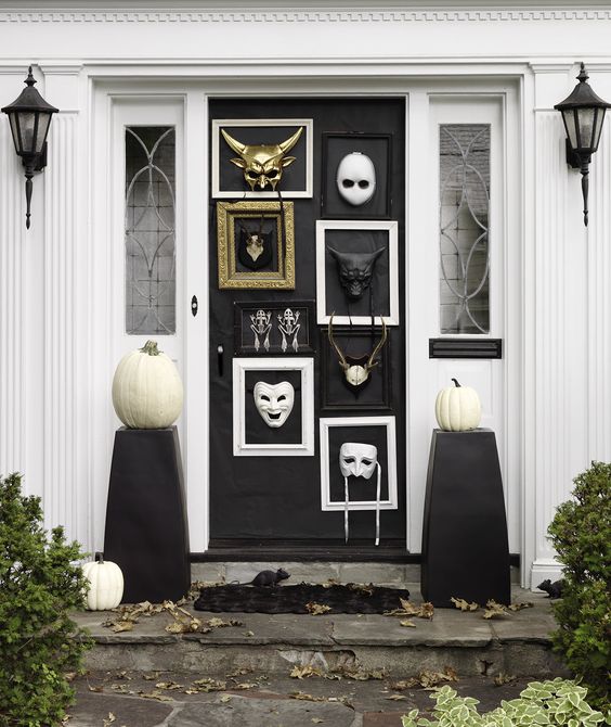 catchy front door Halloween styling with frames with masks, black stands with white pumpkins is a very cool and fresh idea