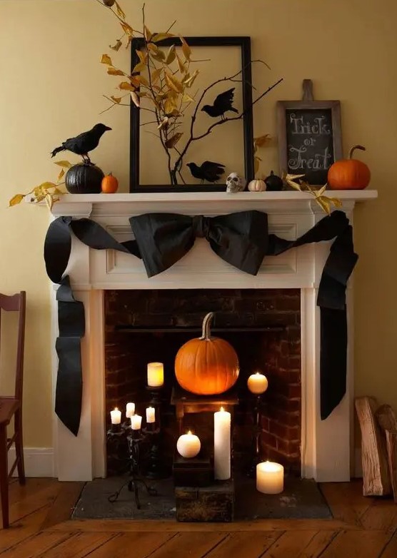 elegant vintage Halloween decor with candles and a pumpkin in the fireplace, a black black bow, blackbirds, pumpkins and leaves