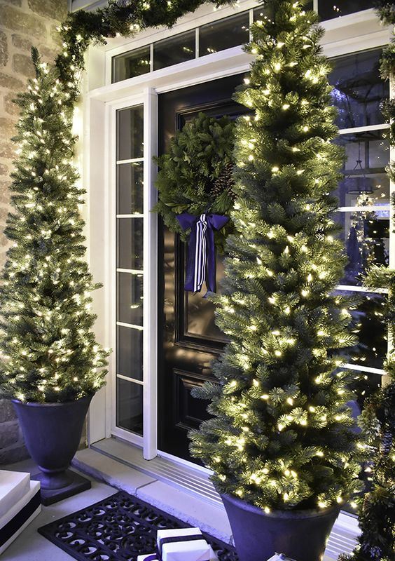 evergreen garlands with lights, Christmas trees with lights in pots and gift boxes for a cozy holiday feel