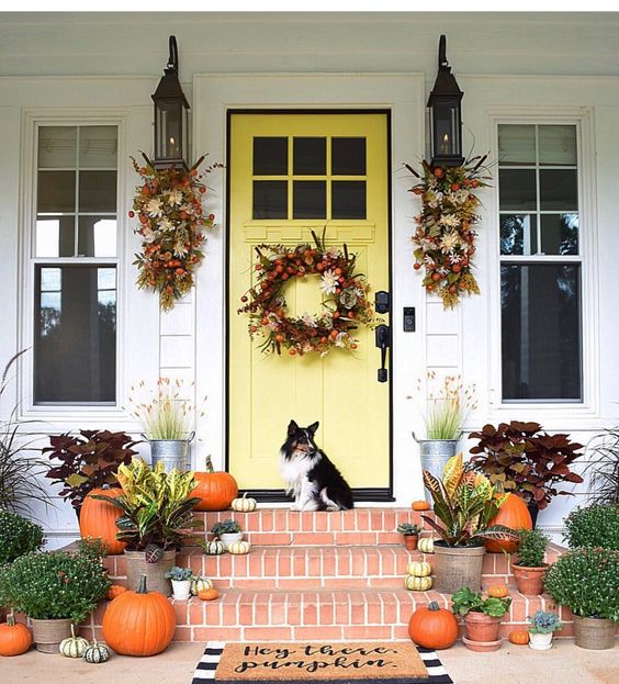 fall posies and a wreath with foliage, berries and feathers, fall blooms and plants in pots and pumpkins on the steps