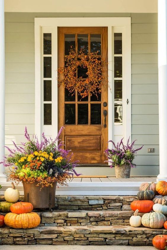 heirloom pumpkins on the steps, bold fall bloom arrangements in buckets, a fall wreath of berries on the door