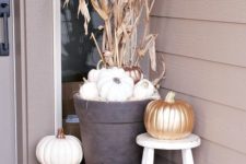 lots of white pumpkins, a wooden candle lantern and a corn husk arrangement to accent the porch and the door