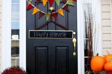 orange pumpkins, bold fall blooms in pots, a colorful bunting and a chalkboard sign for simple Thanksgiving decor