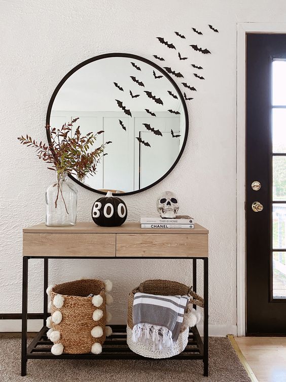 simple and lovely Halloween console table, a black pumpkin, a skull, bats on the wall, a couple of baskets