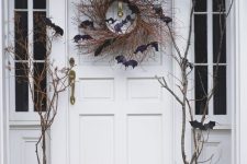 simple rustic Halloween front porch styling with pumpkins, branches, black bats and a twig wreath on the door