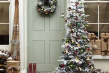 vintage-inspired Christmas front door decor with a cute wreaht with citrus slices and ornaments and a Christmas tree decorated with them, a sleigh with gift boxes and skis