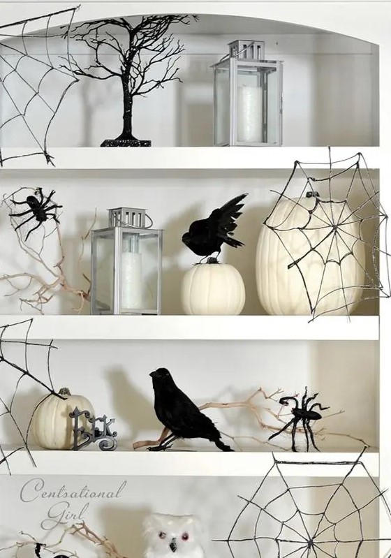 white niche shelves styled with white pumpkins, candles, owls, blackbirds, black spider web and black spiders are perfect