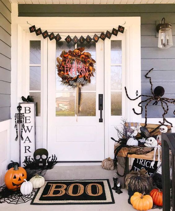 white, orange and black faux pumpkins, a spider, a black bunting, a black mat and spdierwebs, skulls and skeletons for Halloween