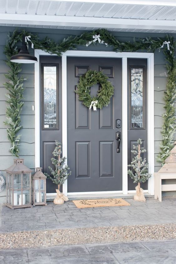 winter wonderland Christmas styling with an evergreen garland with white bows, a wreath and mini trees, candle lanterns