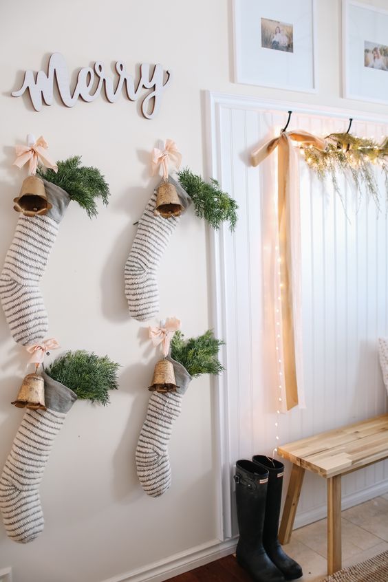 Christmas entryway decor with evergreens, lights, striped stockings with evergreens, vintage bells and calligraphy