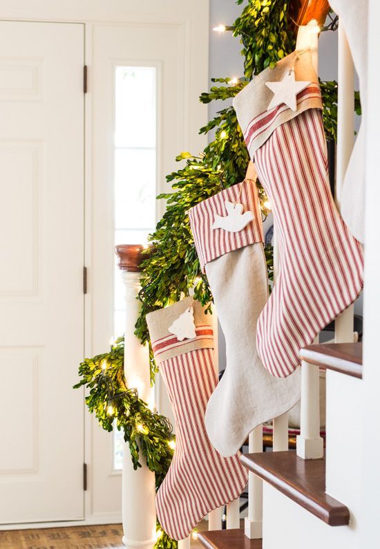 Christmas railing decor with striped stockings, clay tags, evergreens and lights is amazing, chic and cool