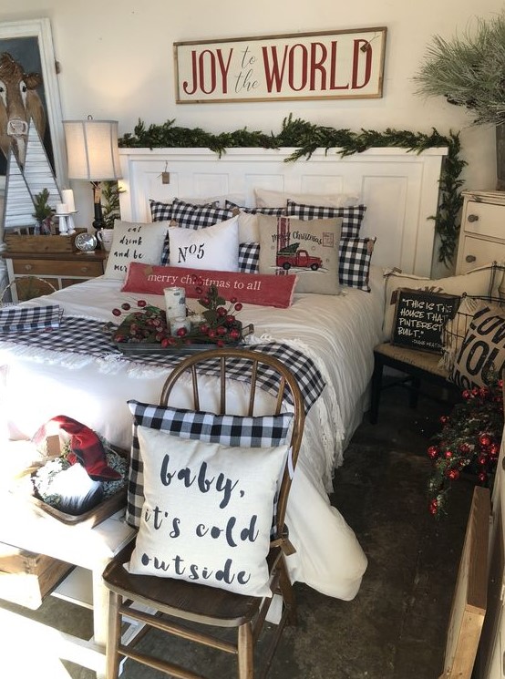 a Christmas bedroom with plaid bedding, evergreens and pinecones, berries and branches plus a sign for a more natural feel
