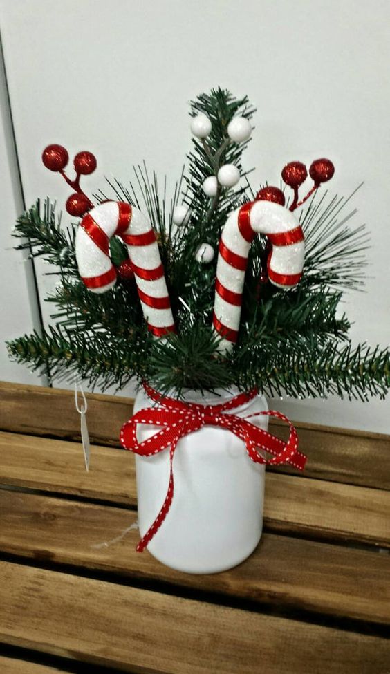 a Christmas centerpiece or just decoration of a white jar with fir branches, candy canes, berries and a red bow is a lovely idea