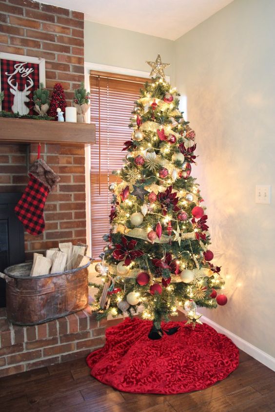 a Christmas tree with lights, gold ribbons, red, neutral and gold ornaments, poinsettia and stars