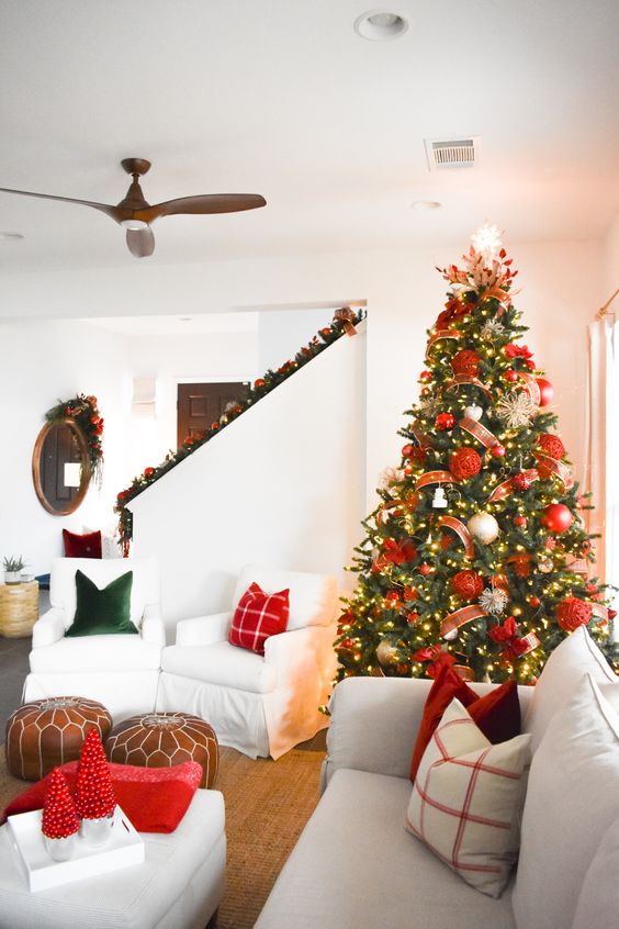 a Christmas tree with lights, red and gold ornaments, ribbons and a shiny snowflake topper