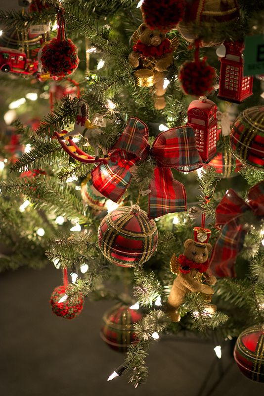 a beautiful Christmas tree decorated with plaid baubles, ribbons, pompoms, mini teddy bears and red phone boxes plus lights is very whimsy