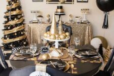 a black and gold tablescape with shiny and glitter ornaments and cone trees, black plates and chargers