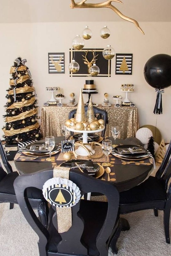 a black and gold tablescape with shiny and glitter ornaments and cone trees, black plates and chargers